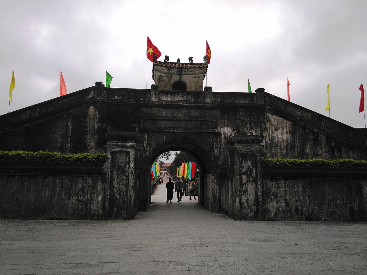 Cổng Thành Cổ Quảng Trị xây gạch đá rêu phong, phía trên có vọng lâu cắm cờ, du khách đi qua cổng