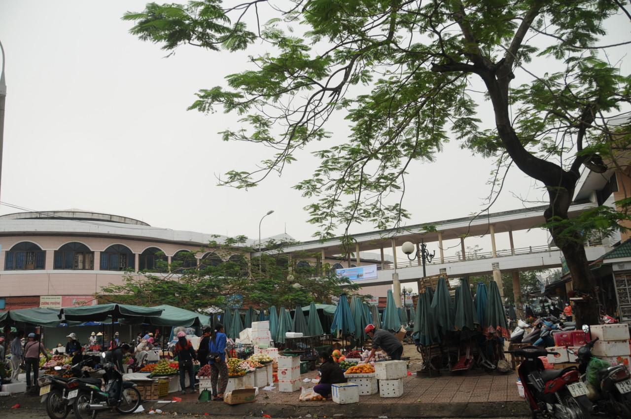 Người bán bày trái cây trên các thùng xốp trắng ở khu chợ Đồng Hới, phía sau là dãy nhà chợ